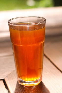 Sıcak ahşap bir yüzeyde bir bardak sıcak çay. Açık havada doğal ışıkla yakalandılar..