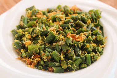 Otantik Balili Lawar Kacang Panjang tabağı, aromatik baharatlar ve baharatlı ve rendelenmiş hindistancevizli uzun fasulyeler sunar..