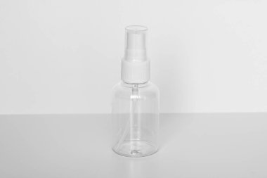Beyaz arka planda beyaz pompalı saydam bir parfüm şişesi. Vücut sisi, dezenfektan ya da saç ürünü ambalajı için minimalist kozmetik şişe modeli.