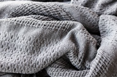 Koyu gri desenli örgü battaniyesi, ağır, kırsal bir dokuması var. Örtülü katları olan doğal kumaş dokusu, ev yaşam tarzı arka planı ve tekstil odaklı grafik tasarımı için uygundur..