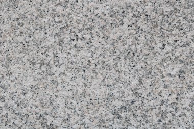 Aşırı dayanıklılığı ve belirgin kristal görünümüyle bilinen gri ve siyah granit taş bir yüzeye yakın çekim. Cephe, anıt ve mutfak tezgahları yapımında kullanılır..