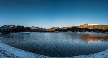 A breathtaking alpine landscape of the Bucegi Mountains in Romania, where a winter sunset casts a golden glow over the snowy peaks