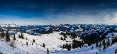 A lone traveler treks through the pristine snow-covered mountains near Kirchberg in Tirol, Austria, embraced by the serene winter landscape