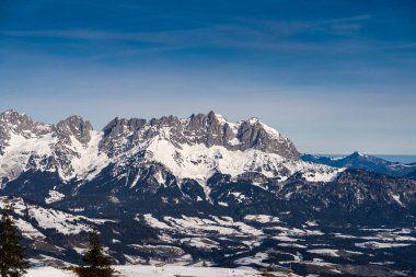 A lone traveler treks through the pristine snow-covered mountains near Kirchberg in Tirol, Austria, embraced by the serene winter landscape