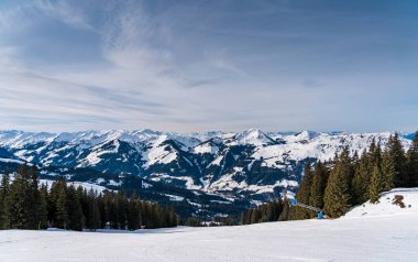 A lone traveler treks through the pristine snow-covered mountains near Kirchberg in Tirol, Austria, embraced by the serene winter landscape