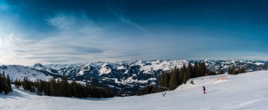 A lone traveler treks through the pristine snow-covered mountains near Kirchberg in Tirol, Austria, embraced by the serene winter landscape