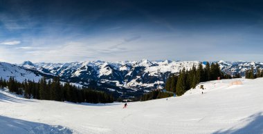 A lone traveler treks through the pristine snow-covered mountains near Kirchberg in Tirol, Austria, embraced by the serene winter landscape
