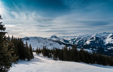A lone traveler treks through the pristine snow-covered mountains near Kirchberg in Tirol, Austria, embraced by the serene winter landscape
