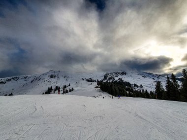 A lone traveler treks through the pristine snow-covered mountains near Kirchberg in Tirol, Austria, embraced by the serene winter landscape