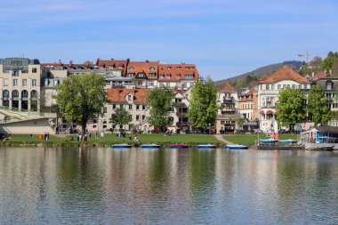Güneşli bir günde Heidelberg 'in deniz kıyısında atmosferik bir şehir manzarası. Ön planda kanocu Neckar Nehri var..