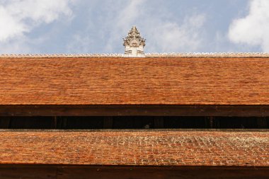 Detaylı, yakın çekim öncelikli olarak aşağıdan bakıldığında geleneksel tapınak yapısının terakotta renkli kiremitli çatılarına odaklanmış. Üst ve alt çatılarda karanlık, yatay bir çizgi var.