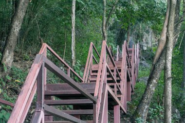 Kireçtaşı uçurumlarına oyulmuş kırmızı çelik yollar boyunca dönüşümlü yolculuk, yemyeşil orman gölgelerinden yükselerek altın tarlaların panoramik manzarasına doğru.