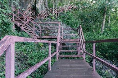 Kireçtaşı uçurumlarına oyulmuş kırmızı çelik yollar boyunca ruhsal bir yolculuk. Ormanın derinliklerinden yükselen gölgeler, altın tarlaların panoramik manzarasına doğru..