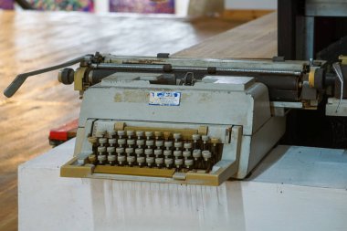 Üstten aşağı, klavye ve arabanın yakın görüntüsü bej ve kahverengi tuşlu eski, tozlu mekanik bir daktilo, parlak ahşap bir zeminde dinleniyor, nostalji ve karınca hissi yakalıyor