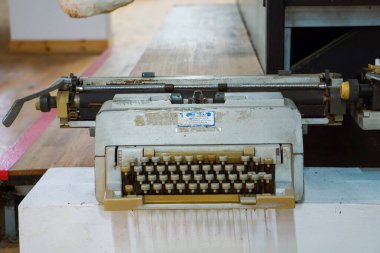 Üstten aşağı, klavye ve arabanın yakın görüntüsü bej ve kahverengi tuşlu eski, tozlu mekanik bir daktilo, parlak ahşap bir zeminde dinleniyor, nostalji ve karınca hissi yakalıyor