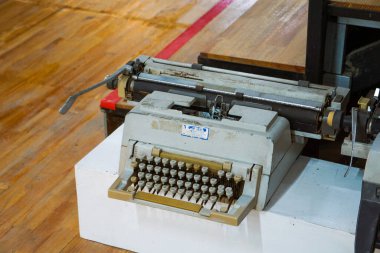 Üstten aşağı, klavye ve arabanın yakın görüntüsü bej ve kahverengi tuşlu eski, tozlu mekanik bir daktilo, parlak ahşap bir zeminde dinleniyor, nostalji ve karınca hissi yakalıyor