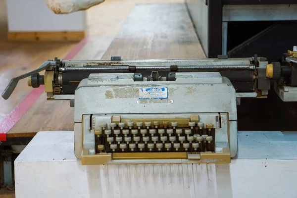 Üstten aşağı, klavye ve arabanın yakın görüntüsü bej ve kahverengi tuşlu eski, tozlu mekanik bir daktilo, parlak ahşap bir zeminde dinleniyor, nostalji ve karınca hissi yakalıyor