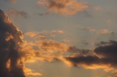 Altın ışık, engin bir akşam gökyüzünde dramatik bulutları aydınlatarak dingin ve büyüleyici bir doğal zemin oluşturur..