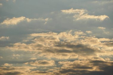 Altın ışık uçsuz bucaksız gökyüzünde dramatik bulutları aydınlatır. Değişen doku ve tonlarla sakin ve atmosferik bir doğal zemin yaratır..