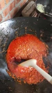 Baharatlı kırmızı biber sosu mutfakta ahşap kaşıkla karıştırılmış.