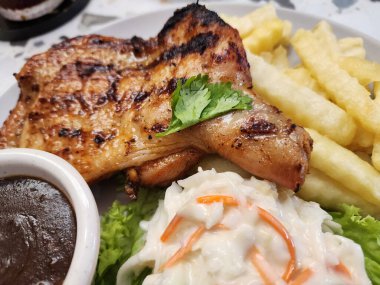 Kızarmış tavuk budu, patates kızartması, lahana salatası ve tabakta bol soslu.