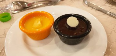 İki Ramekins of Desserts on White Plate: Vanilyalı Krema ve Zengin Çikolatalı Ganache