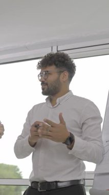 Bir sunum sırasında yeni bir iş planını açıklayan kendinden emin bir erkek yönetici.