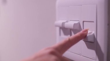 Kadın parmağının birden fazla ışık düğmesini kapatarak odayı karanlığa gömmesi.