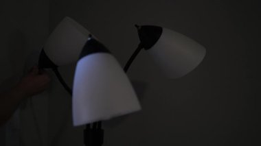 Karanlık bir odada tek tek üç başlı bir lambanın düğmelerini açan insanlar.