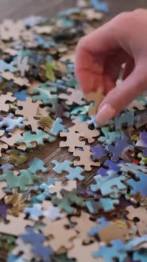 Ahşap bir masanın üzerindeki renkli yapboz parçalarını ayıran bir kadının yakın çekimi.