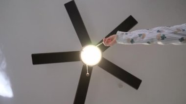 Kadınların eli, modern tavan vantilatörünü açmak için kablo çekiyor.