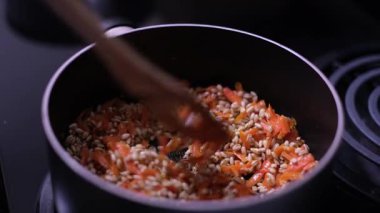 Tahta bir kaşığın yakın plan çekimi inci arpa karıştırır ve bir tencerede doğranmış havuç