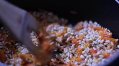 Sıcak bir tencerede karıştırılmış havuçlu inci arpa ve ahşap kaşık sağlıklı bir tarif için.