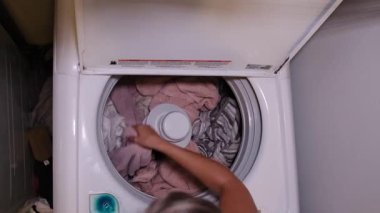 Kadınlar, kirli çamaşırlarını ve havlularını evdeki çamaşır makinesine koyuyorlar.