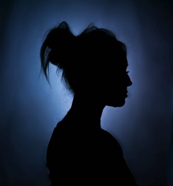 Yumuşak arka planda bir kadının sanatsal silueti. Yumuşak kontrastlı ve karamsar atmosferli minimalist portre konsepti.