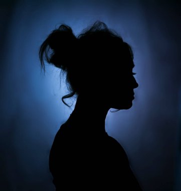 Yumuşak arka planda bir kadının sanatsal silueti. Yumuşak kontrastlı ve karamsar atmosferli minimalist portre konsepti.