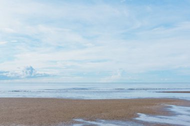 Ufka doğru uzanan denizin yatay bir fotoğrafı, kumlu bir plaj, kabarık bulutlu bir gökyüzü, ve sakin, sakin bir okyanus. Bu resim arkaplan olarak kullanmak için idealdir