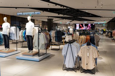 Modern giyim mağazasının iç dekorasyonunda vitrinler, raflar ve şık dekorlar var. Davetkar bir alışveriş ortamı yaratıyor..