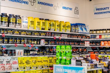 Spor malzemeleri mağazasının iç kısımlarında sporcular ve sağlık meraklıları için destek rafları, protein ürünleri ve fitness ile ilgili ürünler yer alıyor..