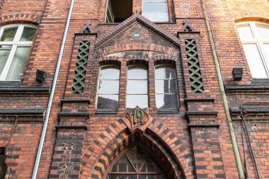 Polonya 'nın Gliwice kentindeki girişi üzerinde kemerli pencereleri olan tarihi tuğla bina cephesinin ayrıntılı görüntüsü..