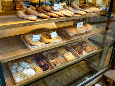 Bir fırının camının arkasında görünür fiyat etiketleriyle çeşitli hamur işleri ve hamur işleri sergileniyor. Sadece editörler kullanır. Kullanılabilir model veya özellik sürümü yok.