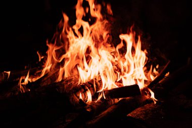 Alevler ve yanan odunlarla dolu bir kamp ateşinin makro görüntüsü. Açık hava, kamp, hayatta kalma ve doğayla ilgili konular için ideal..