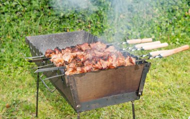 Açık havada ızgara kömür ızgarası ve şiş şiş şiş pişirme şişleri. Geleneksel ızgara et, yaz pikniği ve açık hava yemek konsepti.