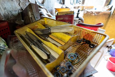 Yıkandıktan sonra çatal bıçak kurutmak için tasarlanmış plastik bir kurutma makinesinde birkaç kirli bıçak var. Konteynır kir içinde ve terk edilmiş bir evin bakımsız mutfağında duruyor..