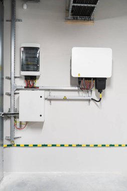 Fotovoltaik sistemlerdeki enerjiyi yönetmek ve dağıtmak için gerekli donanımı gösteren iki elektrik panelinin yanına güneş tertibatı yerleştirildi.