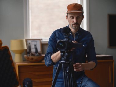 Videograf, ev yapımı çalışma alanında otururken konsantrasyonlu video kamerayı çalıştırıyor