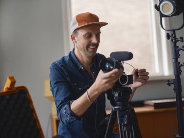 Hevesli kameraman, ev yapımı stüdyo çekimi sırasında heyecanını ifade etmek için kamerayı ayarlıyor.