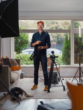 Uzatılmış tripod bacaklı fotoğrafçı profesyonel ışıklandırma arka planına sahip.