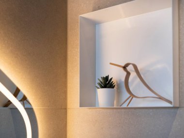 Minimalist kuş anahatlı heykel beyaz sıralı duvar oyuğunda sulu bitkilerle sergilenir