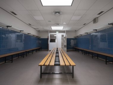 Atletizm tesisinin merkezi perspektifi soyunma odasında dolaplar ve kapı eşiğine uzanan mavi fayanslı duvarlar.